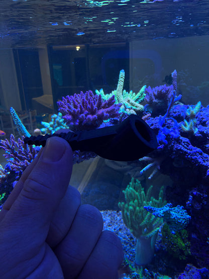 Close view of the 45 degree angled socket on the Reef Secrets PETG frag anchor, held in front of a reef tank